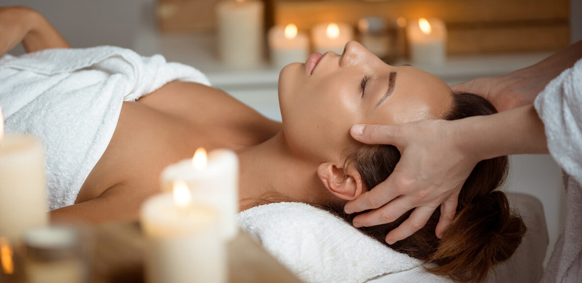 Young beautiful brunette girl having face massage relaxing in spa salon. Eyes closed. Copy space.